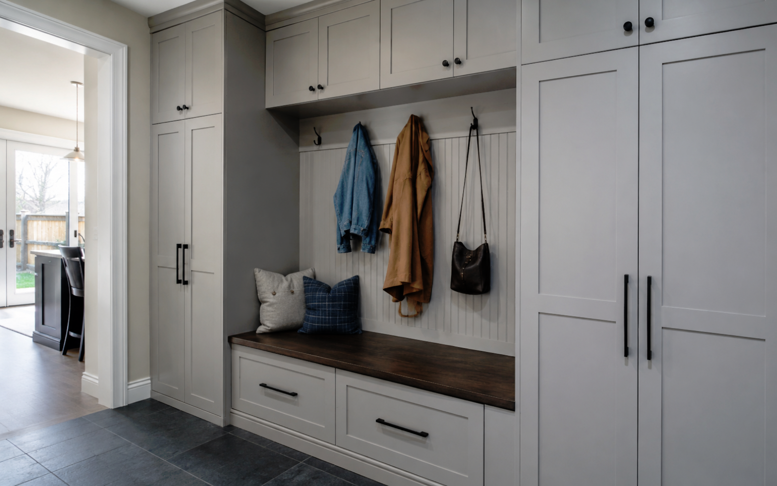Custom built-in mudroom cabinetry in a Toronto home with storage bench, tall cabinets, drawers, hooks, and coordinated hardware
